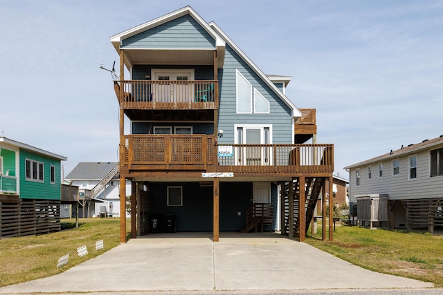 view of front facade featuring stairs, a carport, a front lawn, and driveway