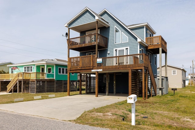 view of front of property featuring a carport, concrete driveway, a front lawn, and stairs