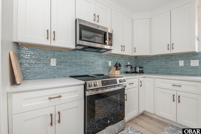 630 Skimmer Ct Lot 20, Corolla, NC 27927 - kitchen with stainless steel appliances, light countertops, white cabinetry, light wood-style flooring, and tasteful backsplash