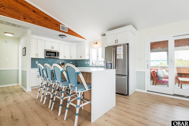 630 Skimmer Ct Lot 20, Corolla, NC 27927 - kitchen featuring stainless steel appliances, light wood-type flooring, white cabinets, a wainscoted wall, and a breakfast bar