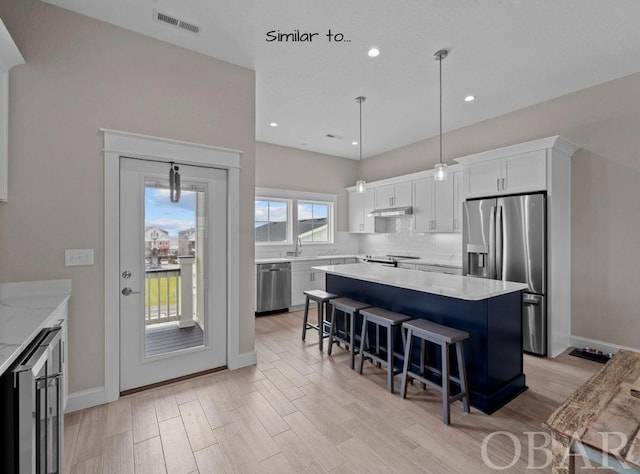 kitchen with visible vents, white cabinets, hanging light fixtures, appliances with stainless steel finishes, and a center island