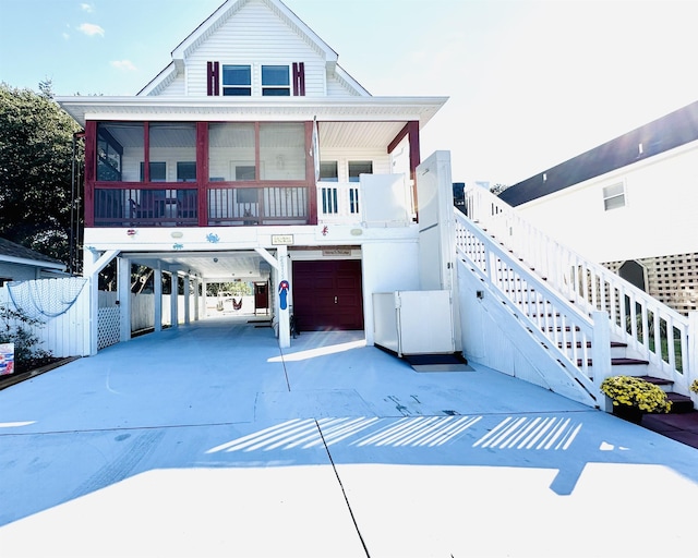 coastal inspired home with a sunroom, stairs, a carport, and concrete driveway