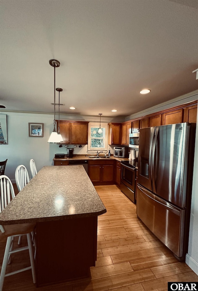 kitchen featuring brown cabinets, light wood finished floors, pendant lighting, and stainless steel appliances