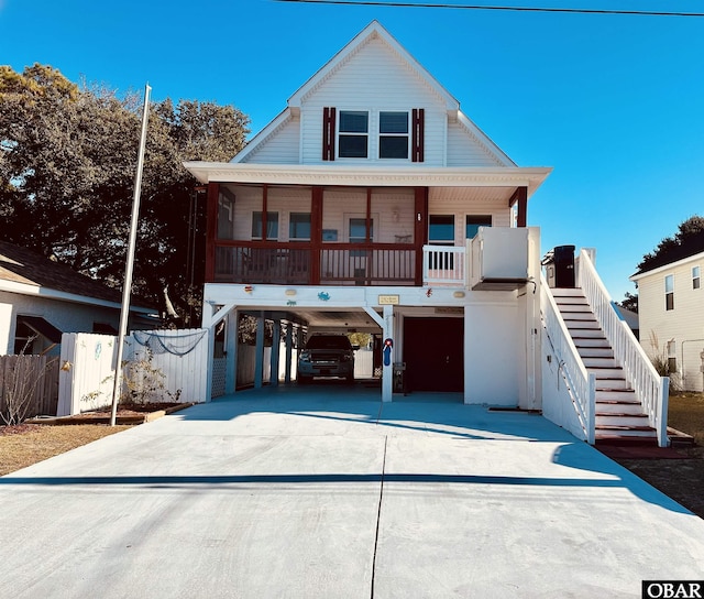 coastal home featuring a carport, a porch, stairway, and concrete driveway