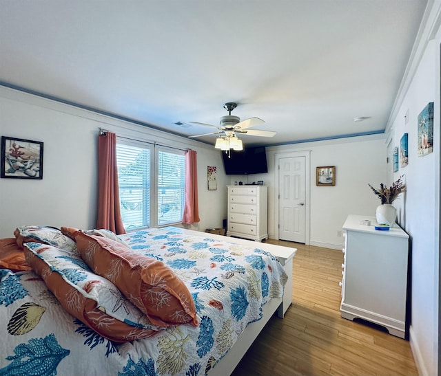 bedroom with ceiling fan, wood finished floors, visible vents, and baseboards