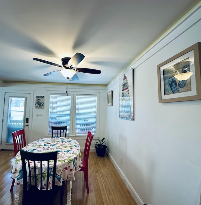 dining area with a ceiling fan, baseboards, and wood finished floors