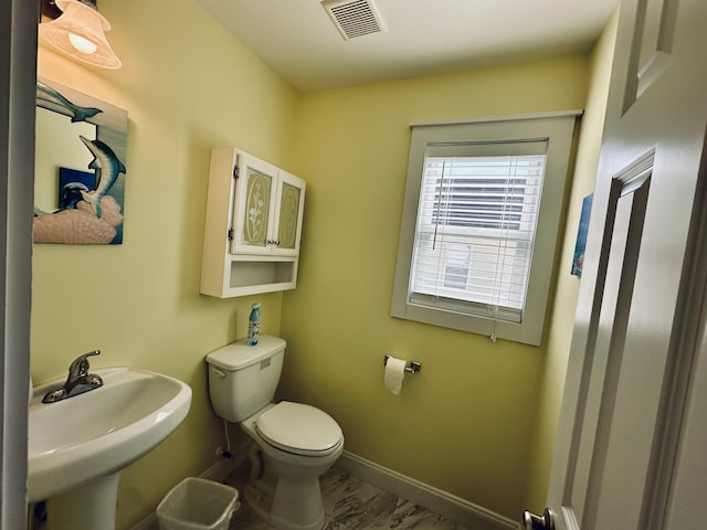 bathroom featuring toilet, a sink, visible vents, and baseboards