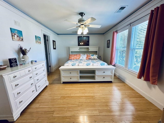 bedroom with light wood-type flooring, visible vents, crown molding, and baseboards