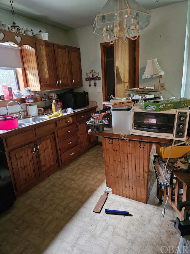 kitchen featuring light floors, brown cabinetry, a sink, and decorative light fixtures