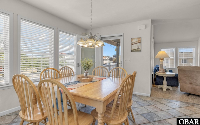 dining area with a chandelier, baseboards, and light stone finish flooring