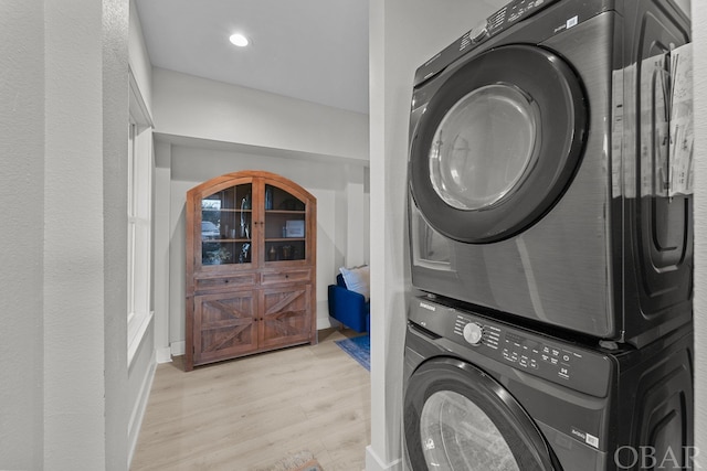 clothes washing area with recessed lighting, laundry area, baseboards, light wood finished floors, and stacked washer and clothes dryer