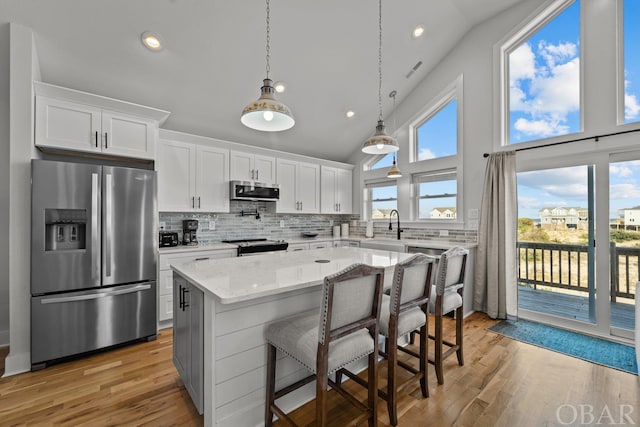 kitchen featuring light stone counters, a breakfast bar area, stainless steel appliances, a kitchen island, and white cabinets