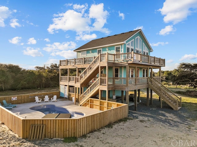 rear view of property featuring stairs, a deck, fence, and a fenced in pool