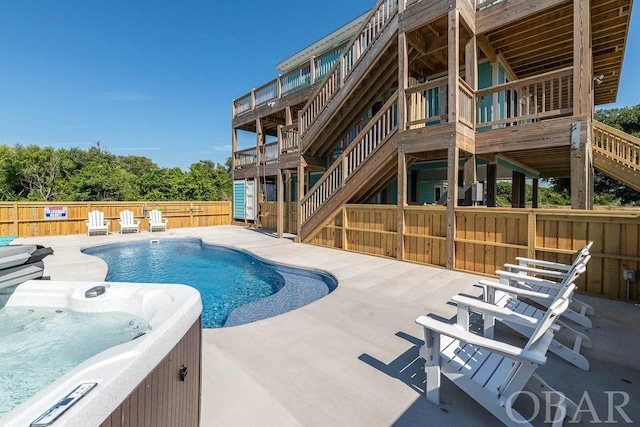 view of swimming pool with stairs, fence, a hot tub, and a patio