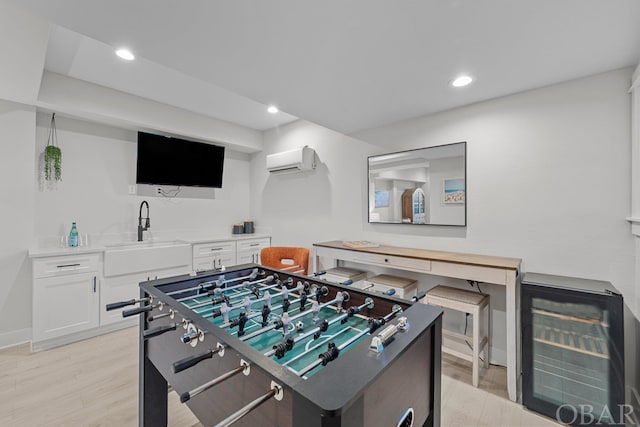 playroom featuring wine cooler, a wall unit AC, recessed lighting, a sink, and light wood-type flooring