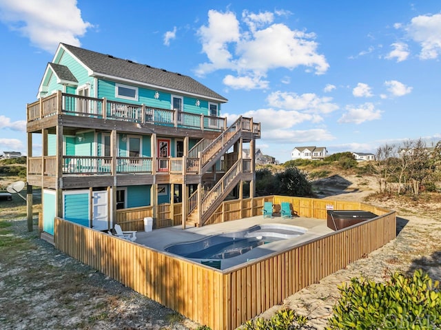 rear view of property featuring a fenced backyard, a jacuzzi, and stairs