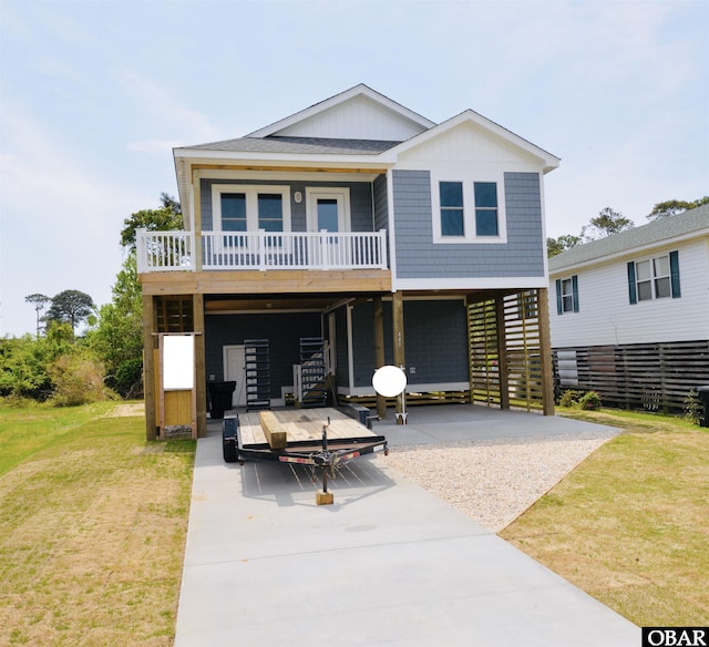 rear view of house featuring a yard, a porch, a carport, stairs, and concrete driveway