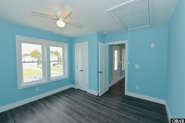 empty room featuring dark wood-type flooring, attic access, baseboards, and visible vents