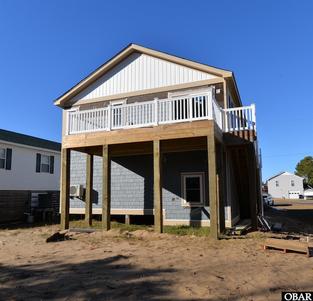 rear view of property with board and batten siding and a wooden deck