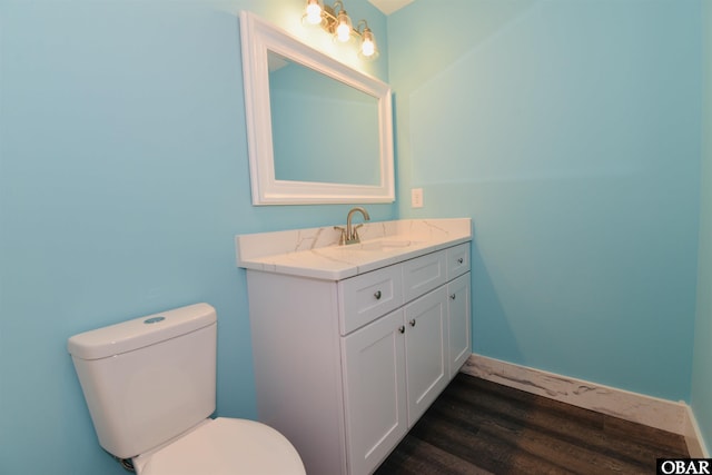 half bath with toilet, vanity, and wood finished floors