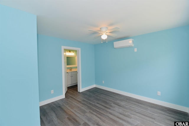 unfurnished bedroom featuring ensuite bathroom, dark wood-style flooring, a sink, an AC wall unit, and baseboards