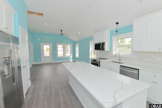kitchen featuring a sink, appliances with stainless steel finishes, light wood-style floors, decorative backsplash, and a kitchen island