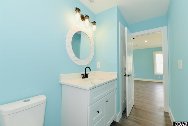bathroom with vanity, recessed lighting, toilet, wood finished floors, and baseboards