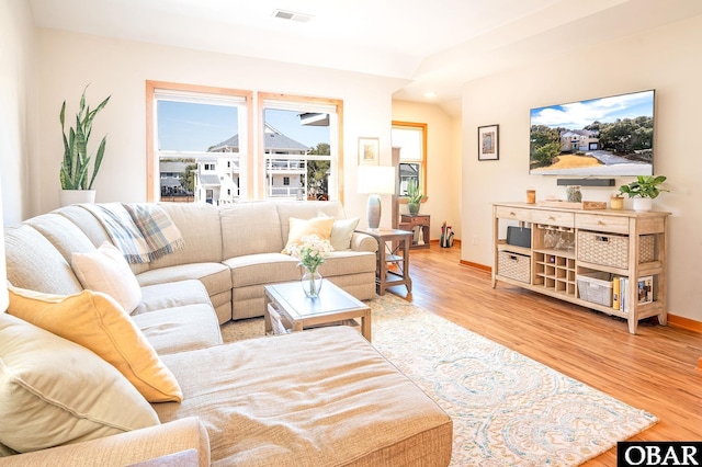 living room featuring wood finished floors, visible vents, and baseboards