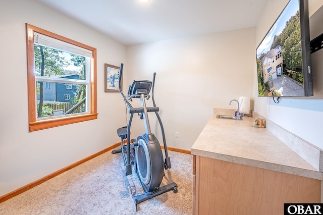 exercise area featuring baseboards, a sink, and light colored carpet