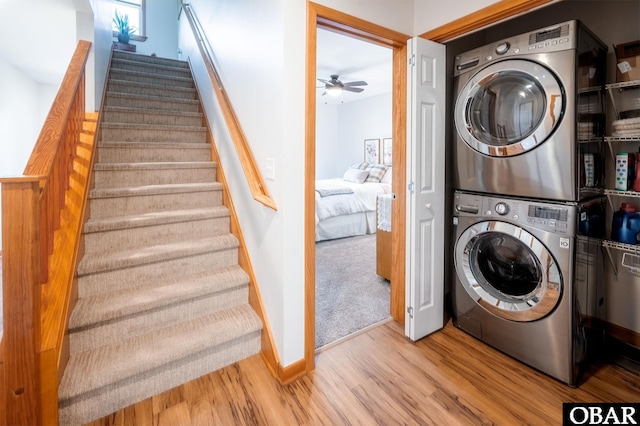 washroom featuring ceiling fan, laundry area, wood finished floors, baseboards, and stacked washing maching and dryer