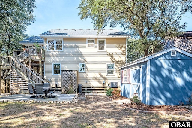 rear view of house featuring an outbuilding, a storage shed, stairs, a wooden deck, and a patio area