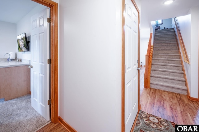 corridor with stairs, wood finished floors, and baseboards