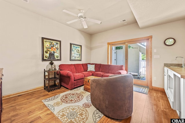 living room featuring visible vents, baseboards, a ceiling fan, and light wood finished floors