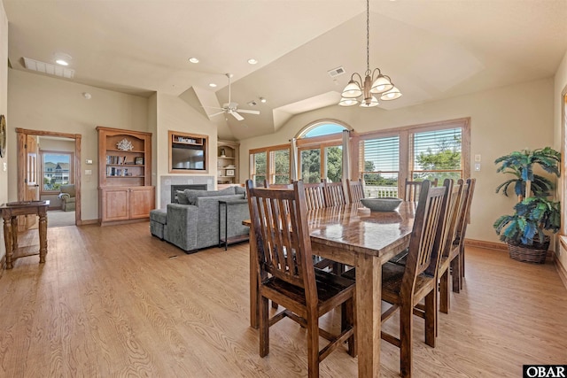 dining room featuring light wood finished floors, visible vents, a fireplace, and built in features
