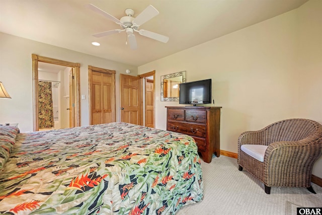 bedroom featuring light carpet, ceiling fan, ensuite bathroom, and baseboards