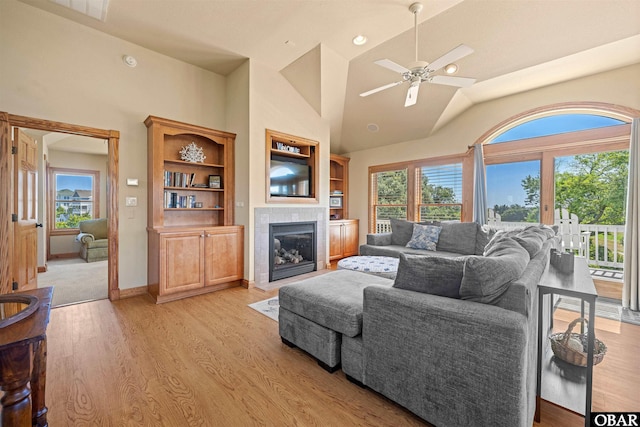 living area featuring light wood finished floors, a tiled fireplace, and a wealth of natural light