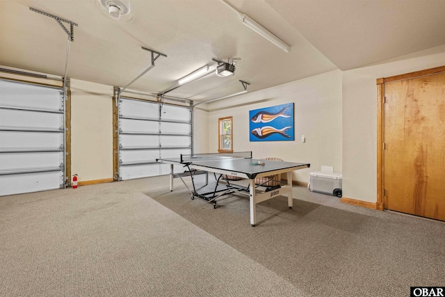 rec room with baseboards, a garage, and carpet floors