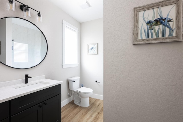 bathroom with baseboards, a textured wall, toilet, wood finished floors, and vanity