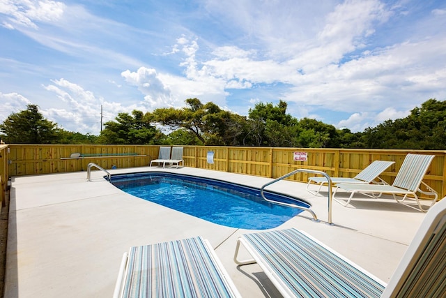 community pool with a patio area and fence