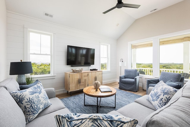 living area with visible vents, vaulted ceiling, a wealth of natural light, and wood finished floors