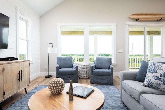 living room featuring a healthy amount of sunlight, vaulted ceiling, baseboards, and wood finished floors