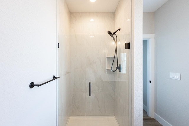 full bath featuring a stall shower and baseboards