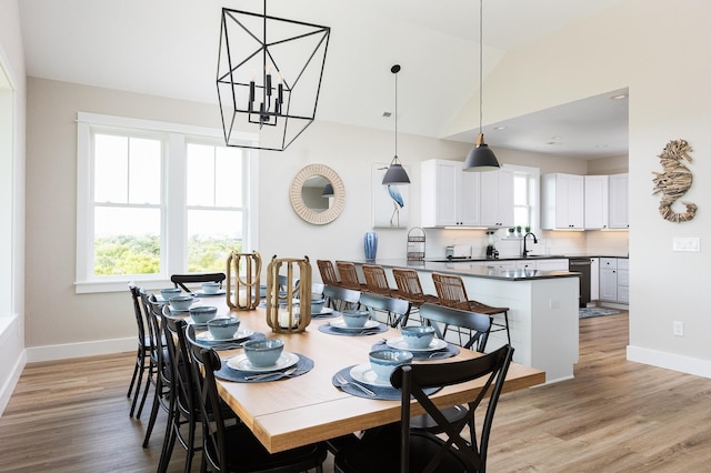 dining space with light wood-type flooring, baseboards, and vaulted ceiling