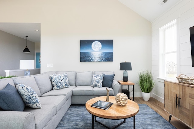 living room with high vaulted ceiling, wood finished floors, visible vents, and baseboards