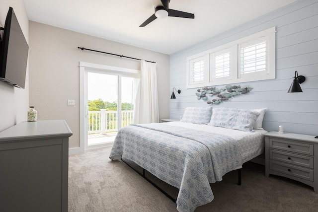 bedroom featuring access to exterior, ceiling fan, wooden walls, and carpet flooring