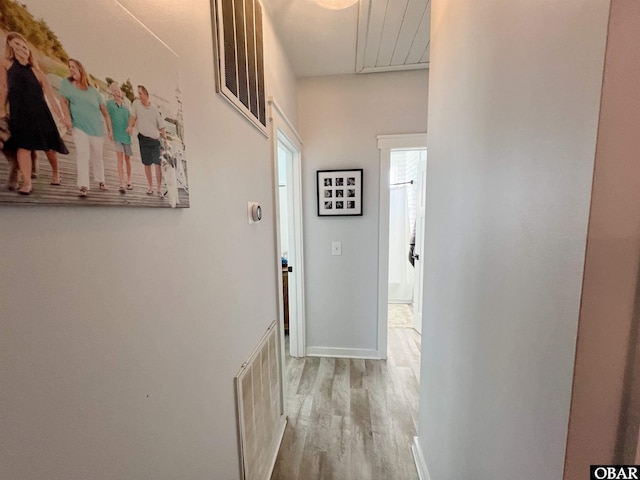 hallway featuring light wood-type flooring, visible vents, and baseboards