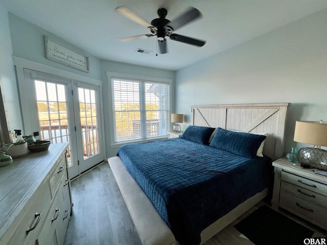 bedroom with access to exterior, a ceiling fan, visible vents, and wood finished floors