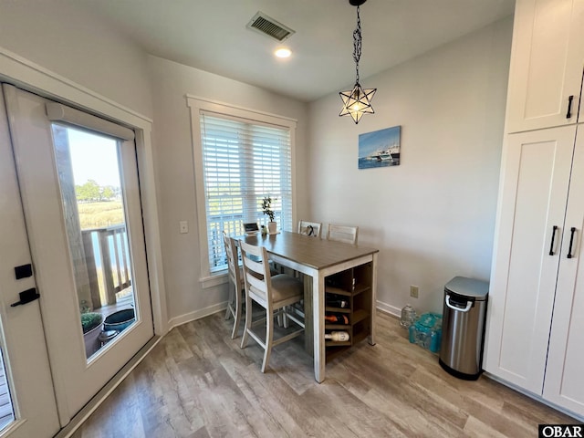 dining area with visible vents, light wood-style flooring, and baseboards