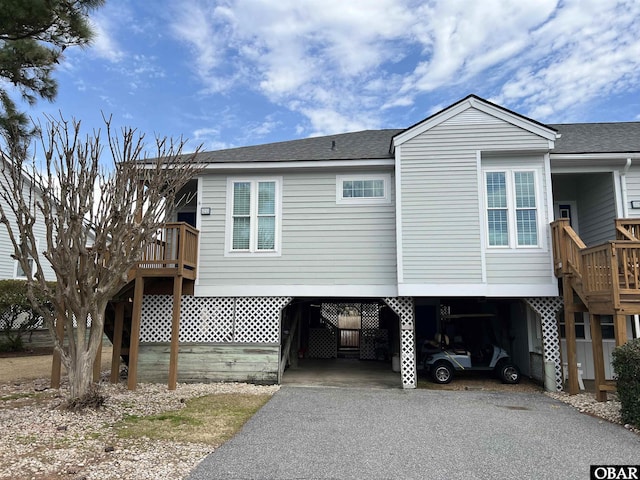 view of side of home featuring a carport, aphalt driveway, and roof with shingles