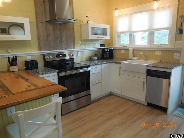 104 Sand Dollar Rd Lot # 23, Ocracoke, NC 27960 - kitchen with appliances with stainless steel finishes, island exhaust hood, light wood finished floors, white cabinets, and backsplash